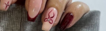 Stylish burgundy Gelx Extension and nude nail art design with minimalist red patterns at Riri Nails salon in Muscat, Oman.